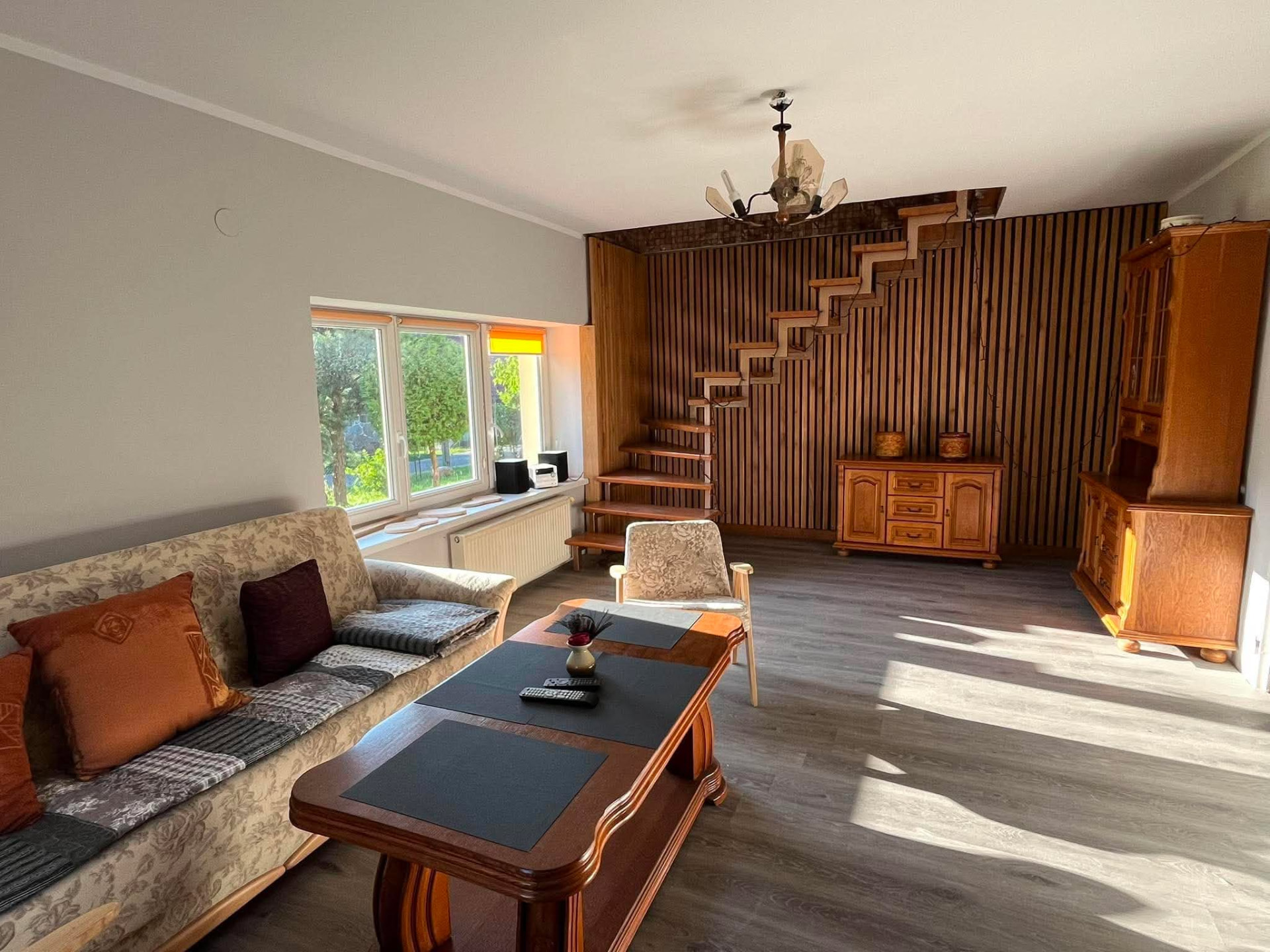 Wielki salon z sofą i drewnianą ścianą w domu w Widrynach
